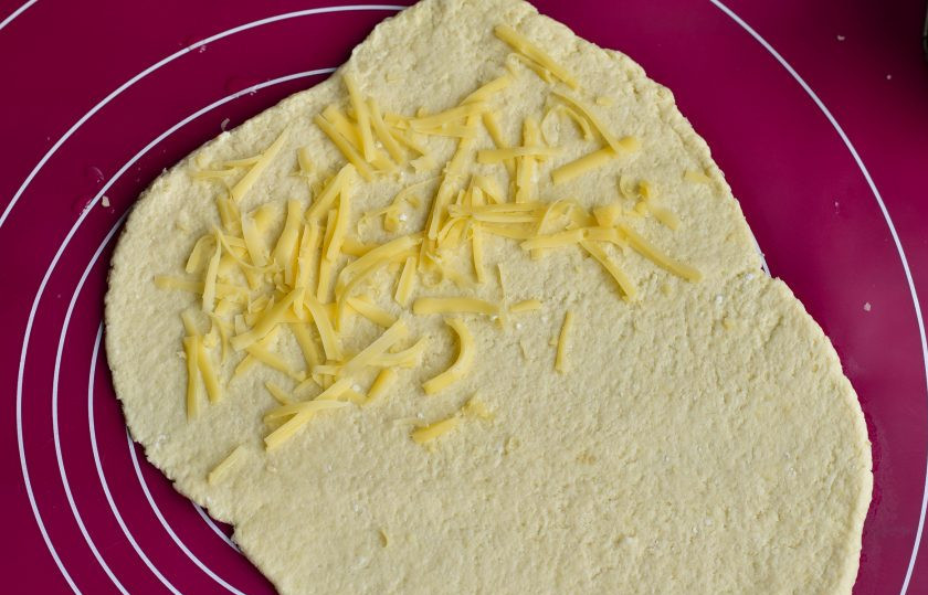 1. Этап. Творожно-сырные палочки: На один край выложите натертый на крупной терке сыр (1/3 часть).