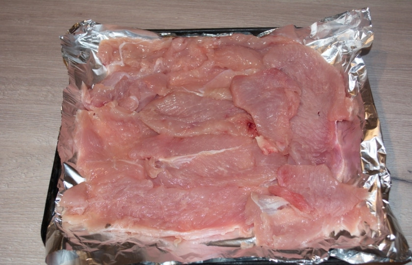 1. Этап. Мясо по-французски из куриного филе: На противень стелим листик фольги. Смазываем его растительным маслом. На фольгу выкладываем отбитое куриное филе.