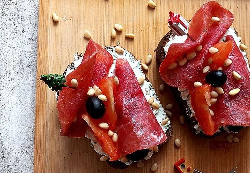 1. Этап. Закусочные брускетты: В свободное место выкладываем дольки помидора, оливки и присыпаем орехами кедровыми.