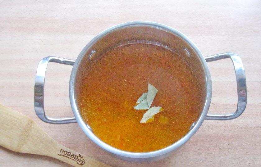 1. Этап. Солянка из судака: Добавьте в кастрюлю с рыбным бульоном лук с огурцами и томатной пастой. Посолите и поперчите по вкусу, выложите лавровый лист.