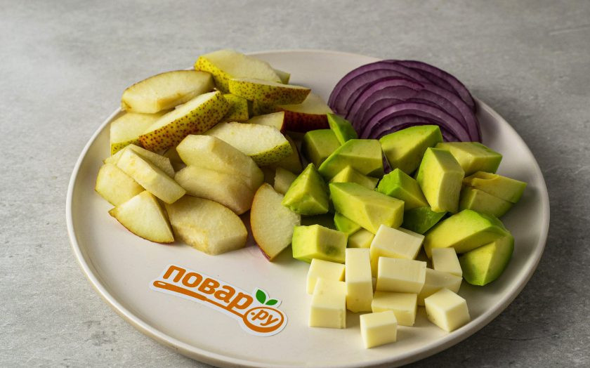 1. Этап. Салат из авокадо с грушей и сыром: Авокадо очистите от кожуры, удалите косточку, нарежьте ломтиками среднего размера. Сыр нарежьте кубиками, красный лук тонкими полукольцами, грушу помойте, удалите сердцевину, нарежьте на ломтики среднего размера.