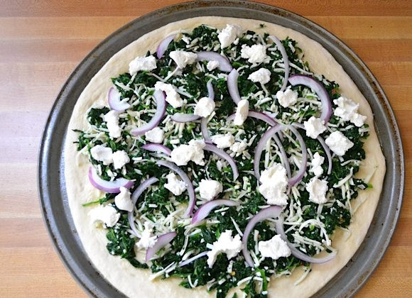 1. Этап. Пицца со шпинатом, луком и сыром: 7. Выложите на тесто сперва шпинат, затем добавьте лук и козий сыр.