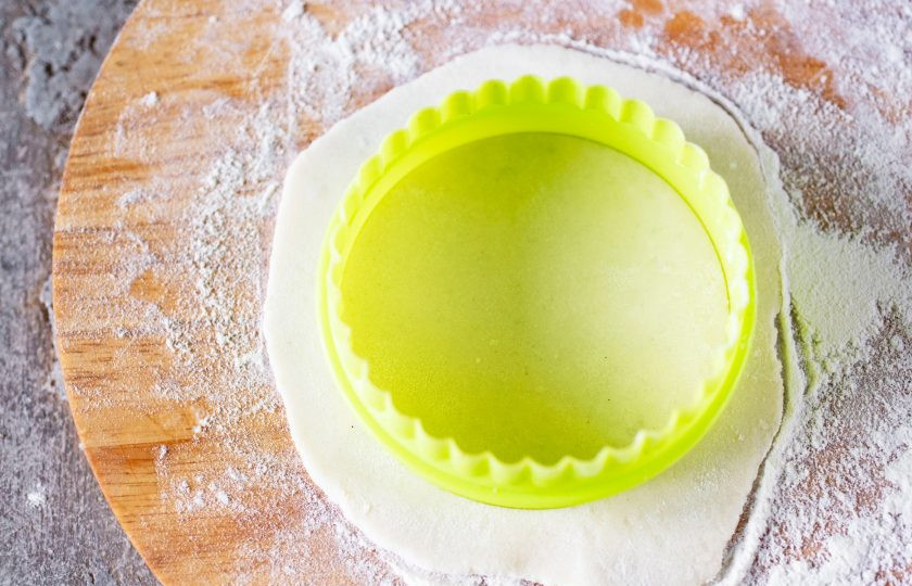 1. Этап. Вареники из рисовой муки: Теперь приступайте к формовке самих вареников. Хочу предупредить, что это очень непросто — рисовая мука не клейкая и тесто очень хрупкое, норовит порваться. Поэтому потребуется некоторая сноровка — я пару штук вареников испортила прежде, чем у меня получился удовлетворительный результат. Сначала хорошенько припылите рабочую поверхность рисовой мукой, затем отщипывайте небольшую часть теста и очень аккуратно раскатывайте в лепешку, но она при этом не должна быть очень тонкой — 2-3 мм. толщиной примерно. Я подравняла лепешку кондитерской вырубкой.