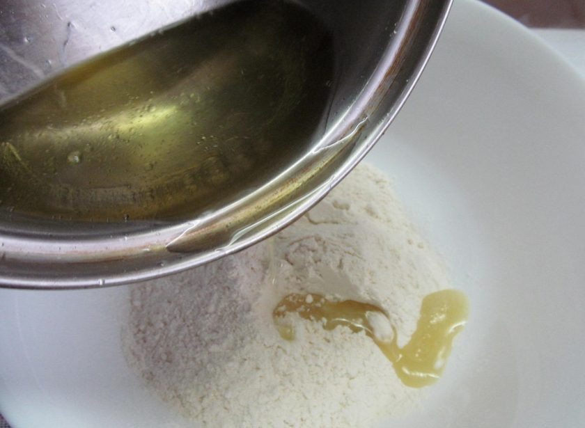 1. Этап. Пирожки из заварного теста с тунцом: В муку влейте кипящую жидкость и сразу перемешайте ложкой.
