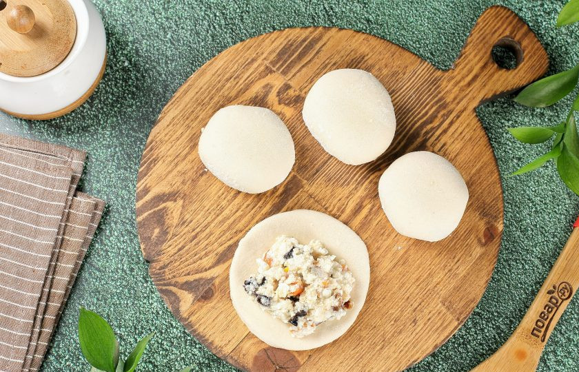 1. Этап. Пирожные Лотосы с творогом и сухофруктами: Выложите по центру начинку, тщательно защипните края к центру и переверните.