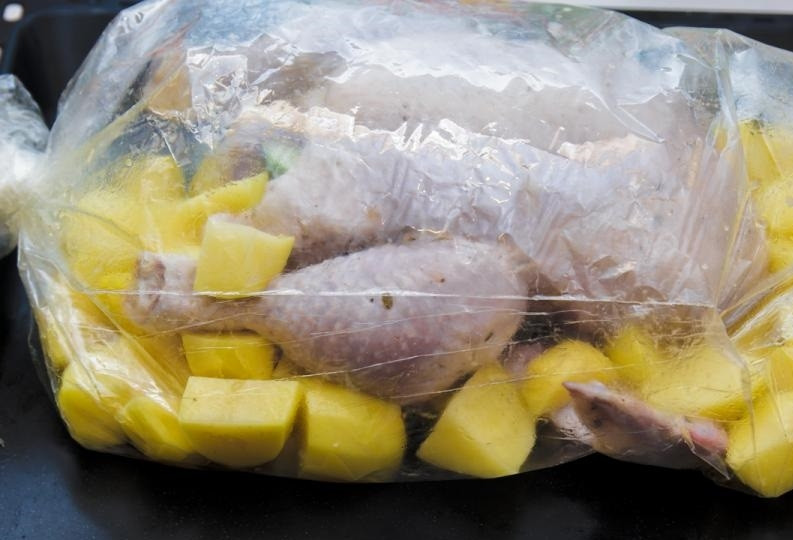 1. Этап. Ароматная курица в рукаве: 4. Возьмите рукав для запекания, отрежьте с учетом того, что в нем будут запекаться курица и картофель. Нафаршируйте курицу яблоками. Вложите картофель в рукав, на картофель положите начиненную курицу. Завяжите рукав с обеих сторон, сделайте несколько отверстий сверху в рукаве.