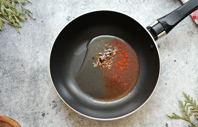 1. Этап. Чесночные стрелки по-корейски: В сковороду налейте растительное масло и разогрейте на среднем огне. Всыпьте специи и жарьте в течение 20 секунд, перемешивая.