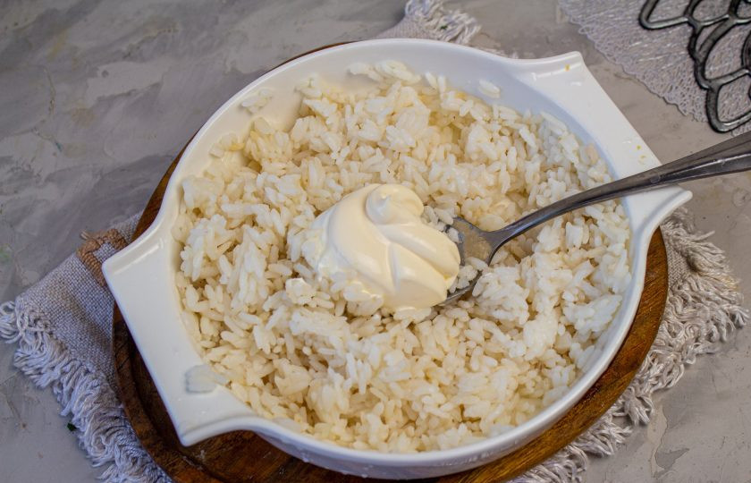 1. Этап. Салат с копченой курицей, черносливом и грецкими орехами: В остывший рис добавьте 1-1,5 столовые ложки майонеза и перемешайте.