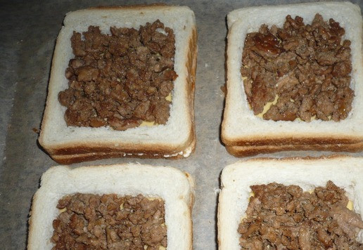 1. Этап. Горячие сэндвичи с фаршем индейки: Поджаренный фарш из индейки выкладываем в каждую вырезанную ячейку в хлебе.