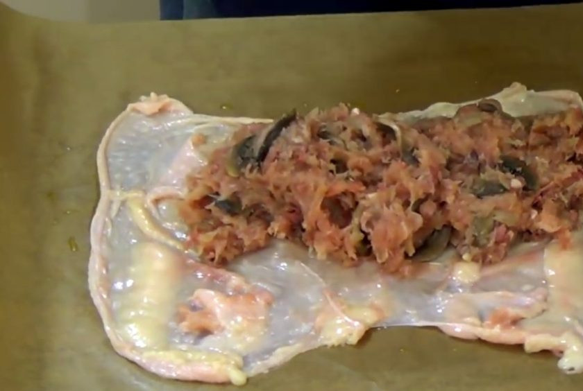 1. Этап. Куриный рулет с грибами и печенью: 4. Добавьте обжаренный лук, обжаренные шампиньоны и хорошо перемешайте. Бумагу для выпечки смажьте маслом, разложите на ней куриную кожу, сверху выложите фарш и сверните рулет.