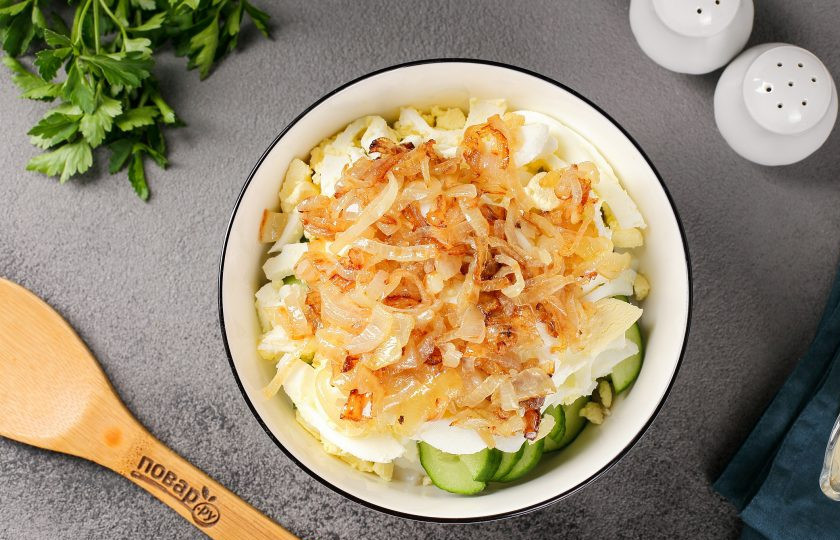 1. Этап. Кальмаровый салат с огурцом: Лук нарежьте перьями и обжарьте на сковороде до золотистого цвета. Добавьте к остальным ингредиентам.