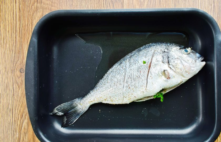 1. Этап. Дорадо по-средиземноморски: По тушке рыбы сделайте два косых надреза с обеих сторон, посолите, брызните оливковым маслом, поместите в форму для запекания. Поставьте в разогретую до 240 градусов духовку на 10 минут.