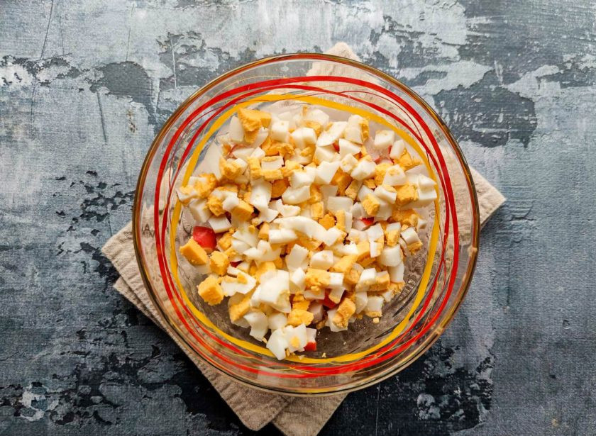 1. Этап. Крабовый салат с грецкими орехами: Вареные яйца очистите от скорлупы, мелко нарежьте и добавьте к крабовым палочкам.