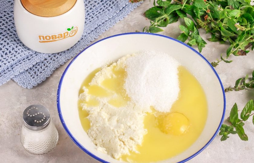 1. Этап. Творожные рогалики Нежнее нежного: Выложите творог в глубокую емкость и помните вилкой. Растопите сливочное масло в микроволновке и влейте в емкость к творогу. Всыпьте 60 грамм сахарного песка, а 20 грамм оставьте на панировку. Добавьте соль, вбейте куриное яйцо и сразу же все перемешайте.