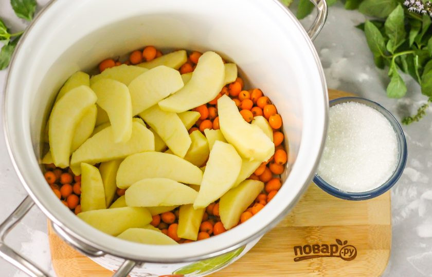 1. Этап. Компот из облепихи и яблок на зиму: Высыпьте ягоды в кастрюлю, в которой собираетесь готовить компот. Промойте яблоки в воде, разрежьте их на четыре части и удалите сердцевинки с семенами. Если яблоки магазинные, то счистите с них кожуру - на ней парафиновый слой. Промойте очищенную яблочную мякоть и нарежьте ломтиками.