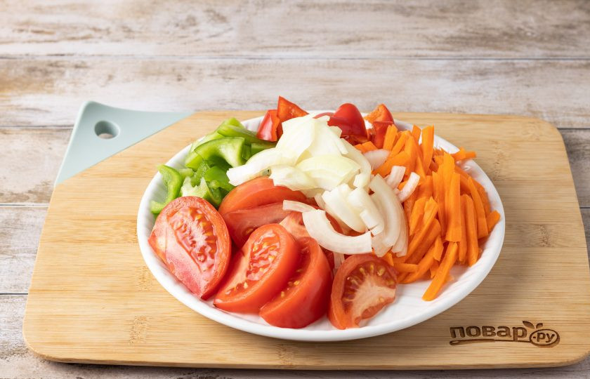 1. Этап. Салат из помидоров, перца, моркови и лука на зиму: Помидоры помойте, удалите плодоножку и нарежьте дольками. Репчатый лук порежьте полукольцами. Морковь очистите и натрите на терке. У болгарских перцев удалите хвостик и семена, затем порежьте полосками.