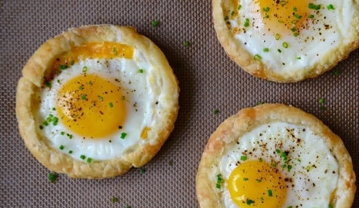 1. Этап. Яичница на слоеном тесте: 4. Выпекайте яичницу на слоеном тесте еще 12 минут. Готовое блюдо сразу посыпьте черным молотым перцем и рубленым зеленым луком.