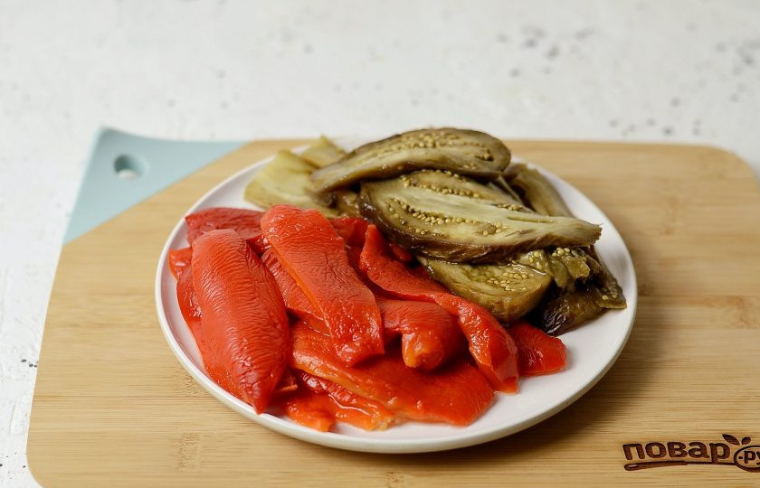 1. Этап. Овощной тьян из баклажанов и болгарского перца: Остудите запеченные овощи. Болгарский перец очистите от кожицы, хвостика и семян. Нарежьте прямоугольными полосами. Баклажан тоже очистите от кожицы, затем нарежьте вдоль на ломтики.