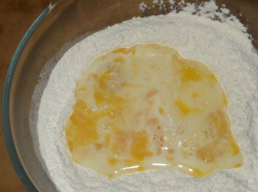 1. Этап. Хворост тонкий хрустящий без водки: Просеиваю муку через сито. Насыпаю ее сразу в яично-молочную смесь. Замешиваю сначала вилкой, а затем - руками. Должен получиться мягкий упругий шарик теста.