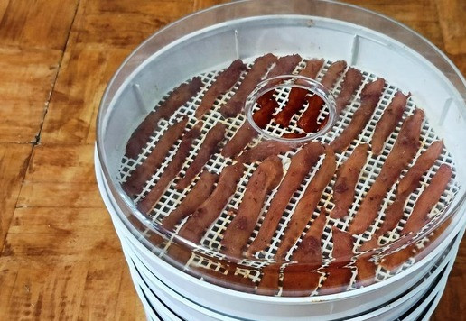 1. Этап. Джерки из индейки по-азиатски: Разложить по лоткам сушилки. В каждой сушилке есть инструкция по приготовлению, ориентируйтесь на неё. Сначала я сушу при температуре 40 С, пока мясо сверху не станет сухим и перестанет пачкать палец, примерно часа два. Потом включаю на 70 С и сушу до готовности. В конце досушиваю снова на 40 С. Лотки переставляю снизу вверх между собой. Джерки должны быть сухими, но не ломкими.