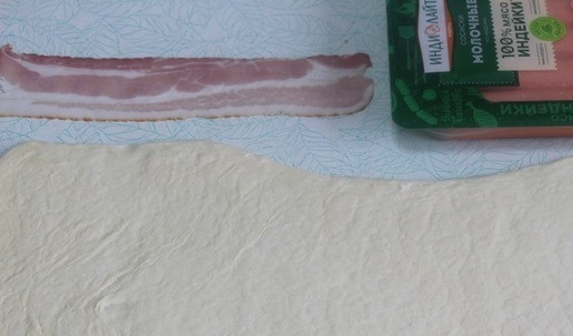 1. Этап. Сосиски в пикантной обертке: Слоеное тесто раскатать. Подготовить бекон и сосиски.