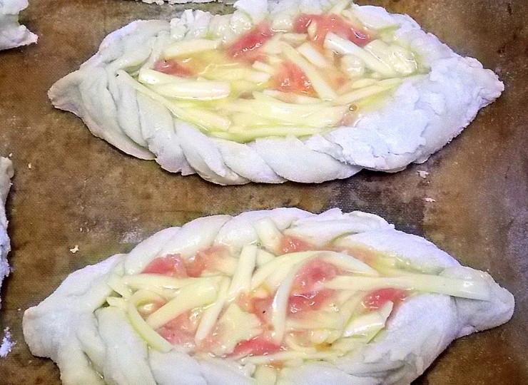 1. Этап. Открытые пирожки Ладья: Натрите сыр на терке, добавьте мелко нарезанную колбасу и сырое яйцо. Перемешайте и выложите начинку в серединку заготовок. Накройте пирожки полотенцем и поставьте в теплое место для подъема.