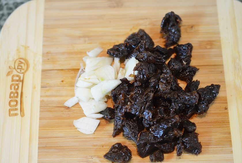 1. Этап. Кальмары, фаршированные грибами и черносливом: Чеснок нарежьте пластинками, чернослив — кубиками.