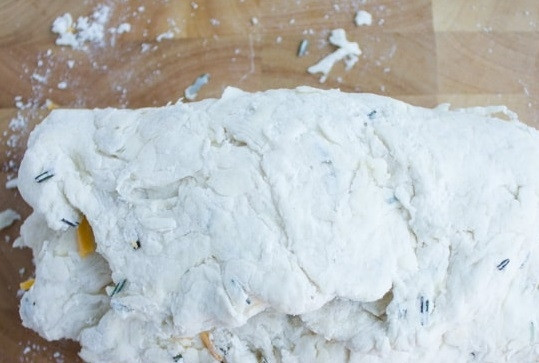 1. Этап. Сырное печенье с клюквой и розмарином: 4. Сверху присыпьте оставшейся частью сыра с клюквой, снова сверните и аккуратно раскатайте тесто.