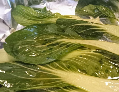 1. Этап. Куриные бедра с мисо и имбирем: В ёмкость для запекания выложить пак-чой. Полить его оливковым маслом.