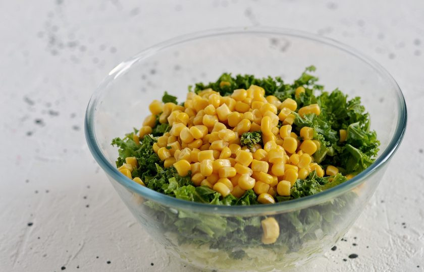 1. Этап. Оладьи из кабачков с кукурузой: Добавьте в миску порубленный кейл и консервированную кукурузу. Посолите, поперчите и приправьте смесь сухим чесноком.