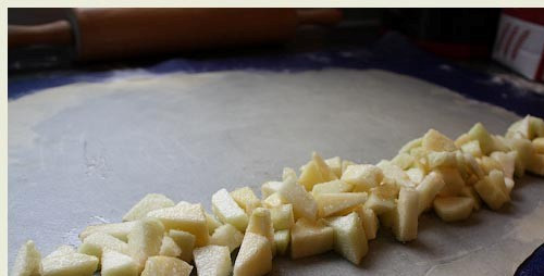 1. Этап. Вертута с яблоками: 4. Вдоль большого края выложите нашу начинку. В данном случае - это яблоки. Теперь можно завернуть нашу вертуту в рулетик. Можете воспользоваться ковриком ли полотенцем. Защипните хорошенько края.