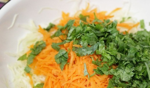 1. Этап. Капустно-морковный салат с яблоком: Добавить морковь к капусте. Туда же выложить кинзу. Если не любите эту ароматную травку, замените её петрушкой.