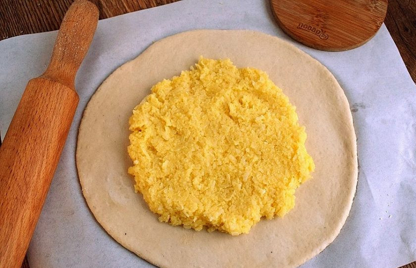 1. Этап. Хачапури по-имеретински классический: Духовку поставьте разогреваться при температуре 200-220 °C. Тесто разомните руками в круглую тонкую лепешку. Можно воспользоваться скалкой. Сыр сулугуни натрите на крупной терке, смешайте с 1 яйцом и 1 ст. л. муки. Тщательно вымесите до однородности и разместите начинку по лепешке, немного не доходя до края.