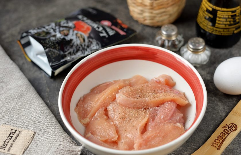 1. Этап. Куриное филе обжаренное в кунжуте Куриный козинак: Нарежьте филе поперек волокон тонкими ломтиками, переложите в глубокую миску, чуть посолите, поперчите по вкусу.