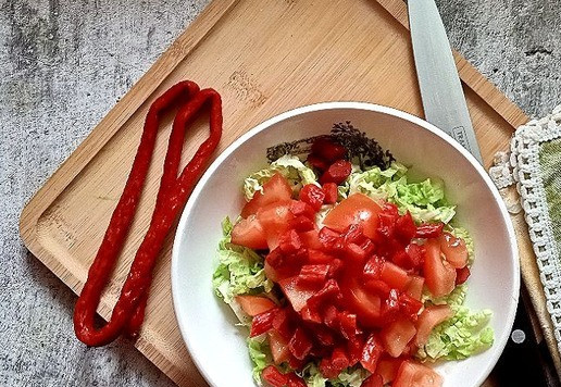 1. Этап. Овощной салат с колбасными снеками: Нарезаем помидор. Я порезала небольшим кубиком. Отправляем в салатник, туда же - и колбаску.