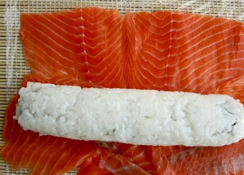 1. Этап. Рецепт суши Филадельфия дома: Нарежьте острым ножом рыбу на тонкие ломтики и разместите их на коврике сплошным слоем, без просветов. Выложим рисовый ролл на рыбу.