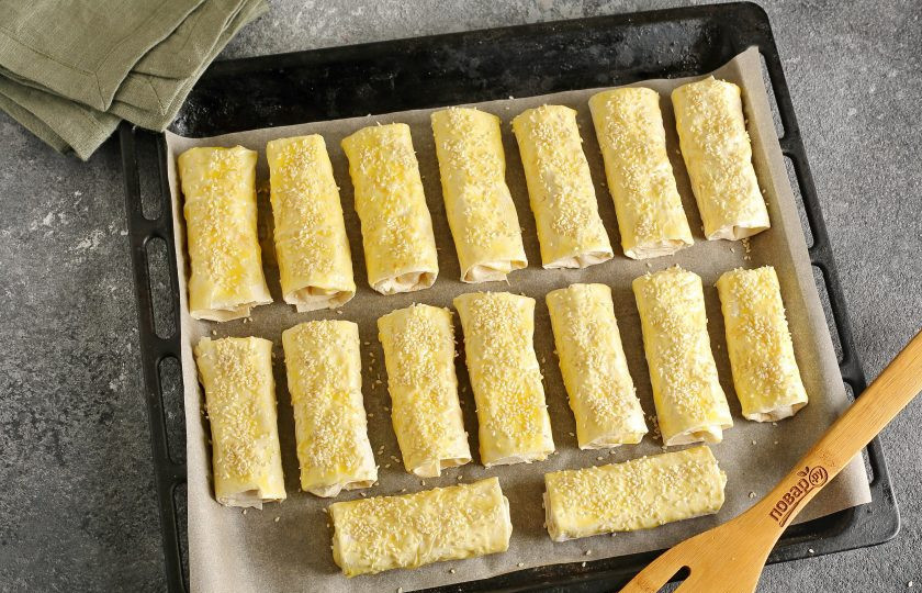 1. Этап. Трубочки из лаваша с картофельной начинкой: Переложите заготовки на противень, смажьте желтком и посыпьте кунжутом. Запекайте в духовке при температуре 180 градусов около 20 минут (до золотистого цвета).