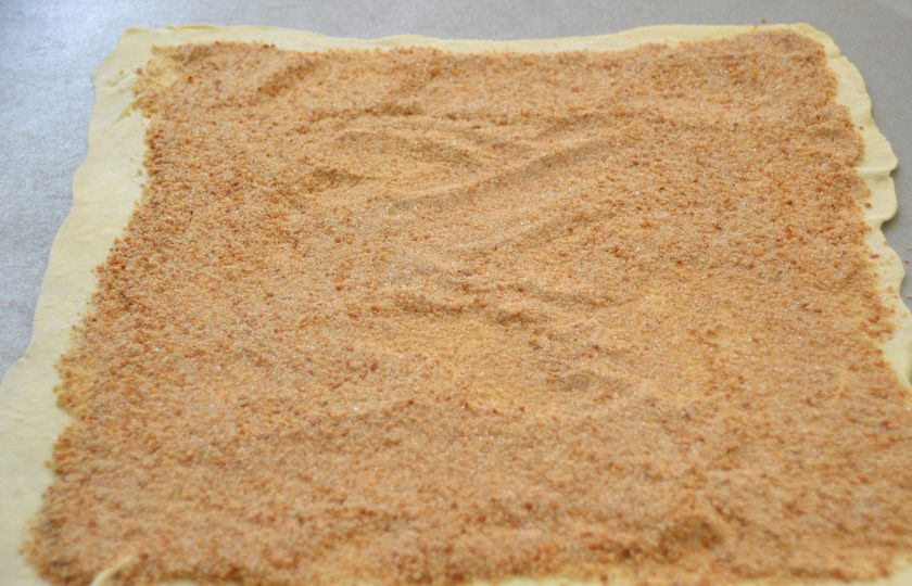 1. Этап. Ленивый яблочный штрудель: Выложите на пласт теста сухарную крошку, разровняйте по всей поверхности, отступив от свободного края на 2-3 сантиметра.