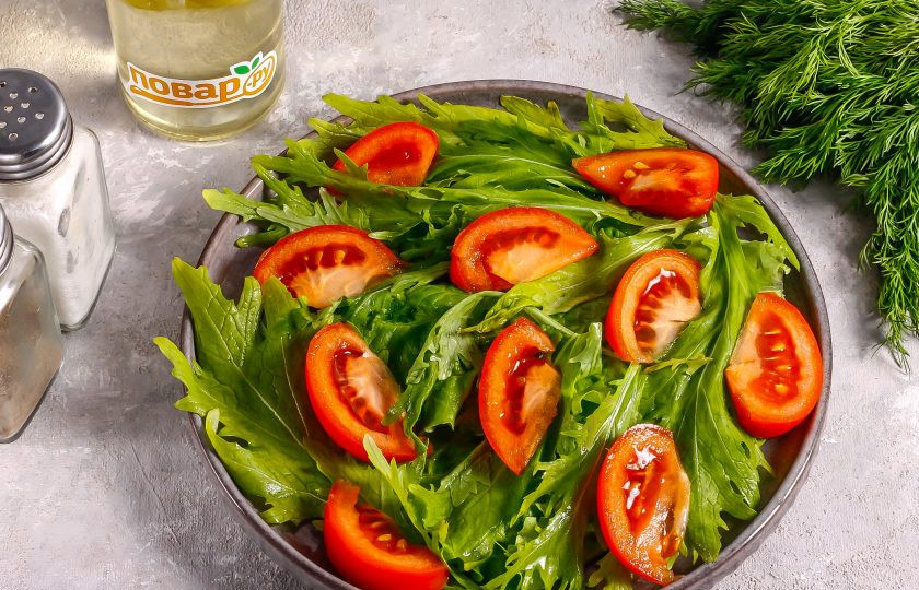 1. Этап. Салат с рукколой и адыгейским сыром: Промойте помидоры в воде, вырежьте зеленые сердцевинки и нарежьте ломтиками. Выложите сверху на зелень в любом порядке.