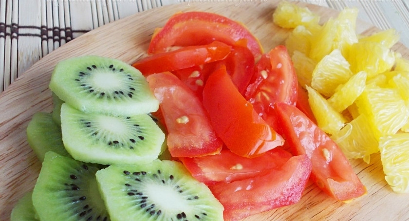 1. Этап. Салат с курицей и киви: Вымойте помидор, киви и апельсин. Киви очистите от кожицы и нарежьте поперек тонкими ломтиками. Помидор нарежьте дольками, а апельсин очистите, разделите на дольки и удалите все белые пленочки и семена, если они есть. Разрежьте на 2-3 части.