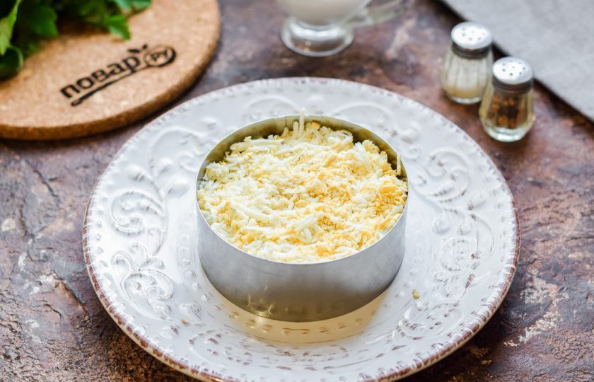 1. Этап. Салат Мачо: Куриные яйца сварите вкрутую, натрите на мелкой терке и выложите в салат.