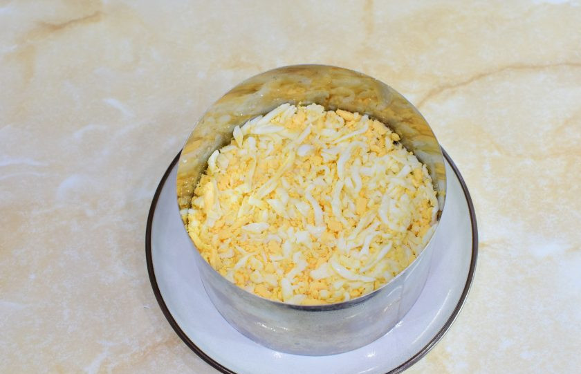 1. Этап. Салат Мимоза с копчёной скумбрией: Потрите яйца на терке и выложите из них следующий слой.