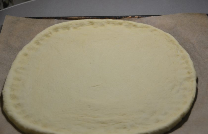 1. Этап. Пицца Примавера: Раскатайте тесто в пласт, перенесите на противень, застеленный пекарской бумагой, сделайте небольшие бортики.