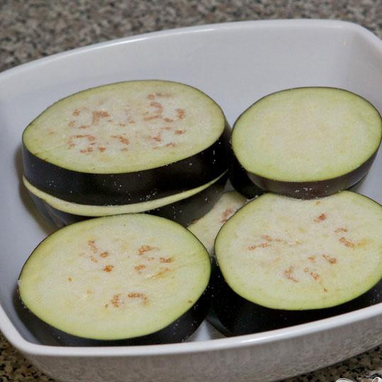 1. Этап. Тушенная утка с баклажанами и картофелем: Порежьте баклажан на кружки толщиной примерно 1.5-2 см. Посолите с обеих сторон и переложите в миску на 15-20 минут.