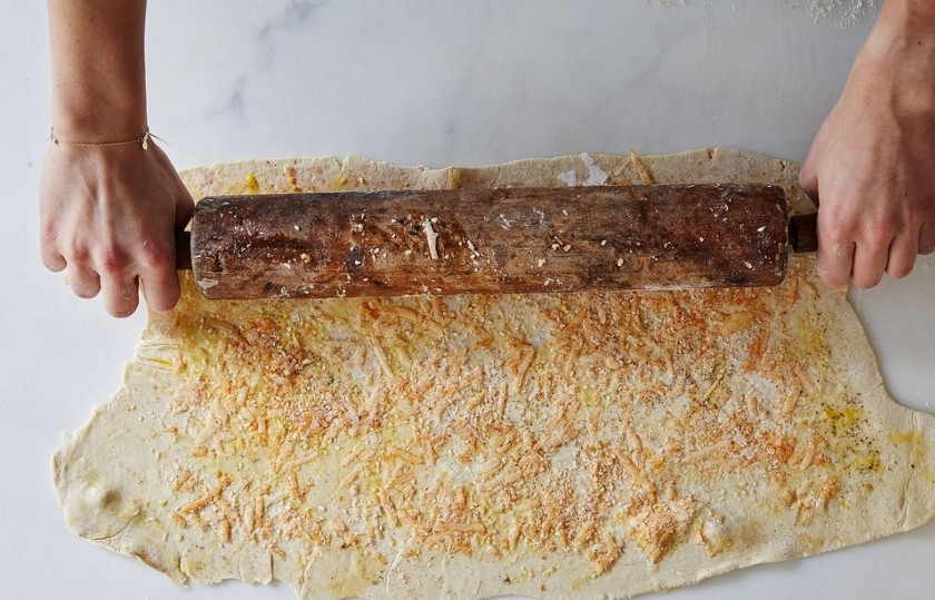 1. Этап. Сырные палочки из слоеного теста: Шаг 6. Смажьте яйцом верх теста, выложите на него оставшийся сыр, посыпьте смесью из специй. Хорошенько прижмите скалкой.