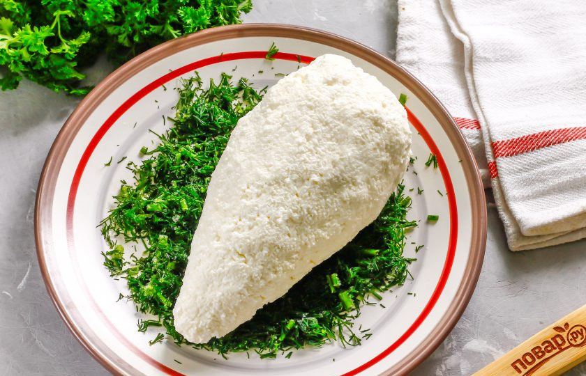 1. Этап. Сырная ёлочка: Укроп промойте в воде, измельчите и выложите на тарелку. Можно использовать нарезанную заготовку зелени с лета. Влажными руками сформируйте из творожной массы конус и обпанируйте его в измельченном укропе.