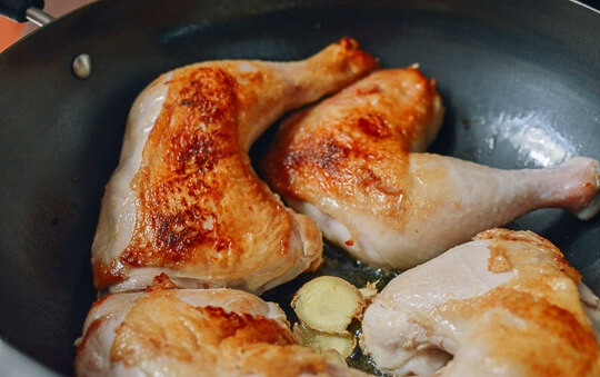 1. Этап. Курица в устричном соусе: Переверните курицу. Выложите в сковороду слайсы имбиря (можно чуть раздавить их ножом) и обжарьте его с двух сторон (по 1-2 минуте с каждой), чтобы он закарамелизовался в масле.