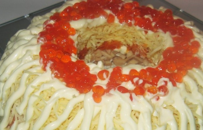 1. Этап. Салат Морская пена: В самом конце посыпьте салат тёртым сыром. Украсьте майонезом в виде волн и икрой. Уберите в холодильник на 40 минут для пропитки, а потом уберите стакан из центра и подавайте салат к столу. Приятного аппетита!