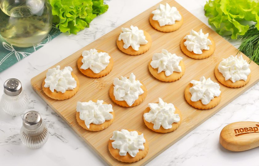 1. Этап. Крекеры закусочные: Творожный сыр выложите в кондитерский пакет и отсадите на крекеры. Если он оказался суховат, добавьте немного сметаны.