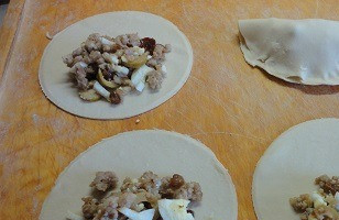 1. Этап. Слоеные пирожки с мясом Эмпанадас: Слоеное тесто тонко раскатать и вырезать кружки диаметром около 12 см. В середину выложить начинку, свернуть пополам и хорошо защипать края.